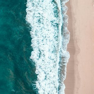 Stunning aerial view of ocean waves hitting a sandy beach in Los Angeles, California.