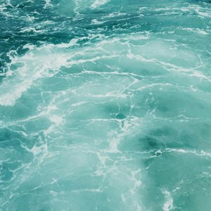 A captivating view of the turquoise and teal waves on the ocean surface, showcasing dynamic water patterns.