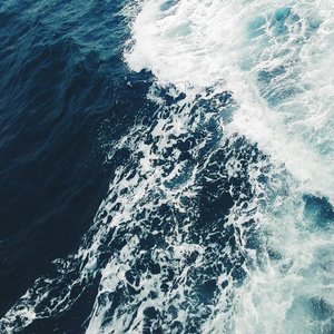 A dramatic aerial shot of ocean waves crashing, showcasing the vibrant blue sea off Cambodia's coast.
