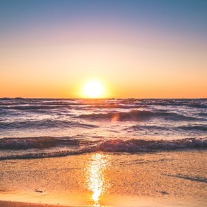 Experience the serene sunset over Ludington Beach with vibrant colors and tranquil waves.