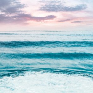Calm ocean waves under a vivid sunset sky at North Shore, Oahu, ideal for surf enthusiasts.