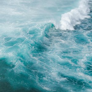 Drone view of turquoise water of ocean with large foamy waves in sunny day