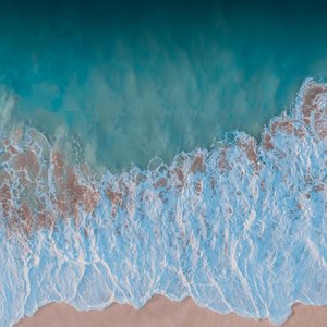 Captivating aerial view of turquoise waves crashing on the sandy shores of Waikiki Beach, Hawaii.