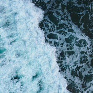 Captivating aerial view of ocean waves crashing, showcasing vivid aqua and deep blue hues.