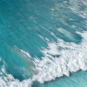Aerial view of bright blue water of sea with foamy waves in sunny day