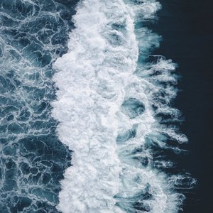 Dramatic aerial view of ocean waves crashing and foaming, showcasing nature's dynamic beauty.