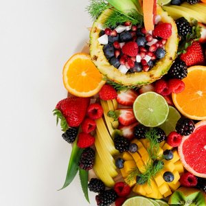 Colorful flat lay of assorted tropical fruits including pineapple, berries, and citrus.