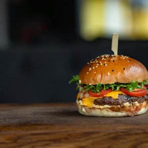 Mouth-watering cheeseburger with fresh ingredients on a wooden surface, perfect for food lovers.