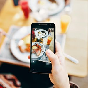 Overhead view of a person photographing a colorful brunch spread with a smartphone.