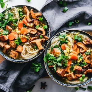 A vibrant noodle bowl with tofu, mushrooms, and fresh vegetables, perfect for a healthy meal.