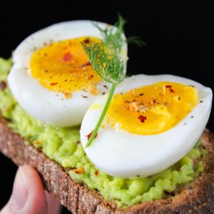A delicious and healthy avocado toast topped with soft-boiled eggs, perfect for a nutritious breakfast.