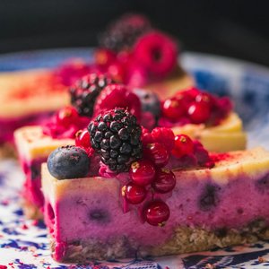 Sliced berry cheesecake topped with vibrant fresh berries and served on a decorative plate.