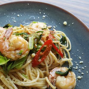 Appetizing shrimp pasta garnished with fresh chili and herbs in a close-up view.