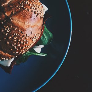 Delicious close-up of a gourmet sandwich with sesame seed bun and spinach on a plate.