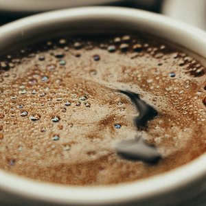 A close-up photo showcasing freshly brewed coffee in a white cup with visible bubbles.